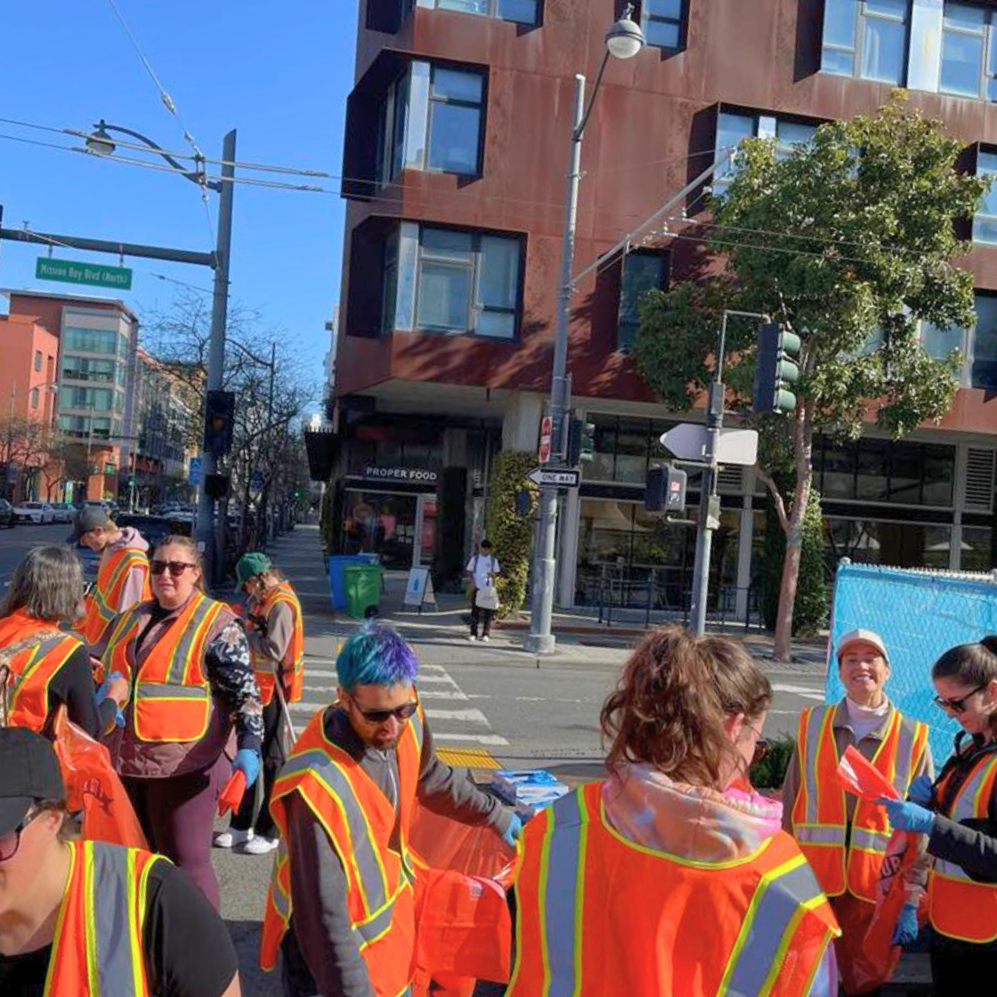 a group of people walking down a street cleaning up trash