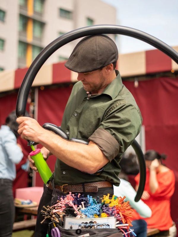 a man wearing a hat blowing animal balloons