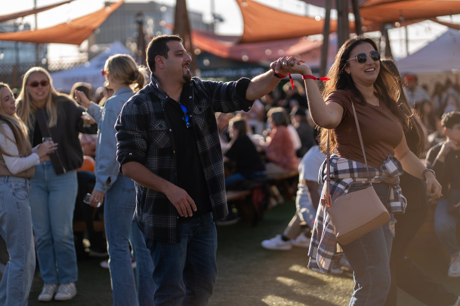 Couple dancing outdoors at a festival with people in the background.
